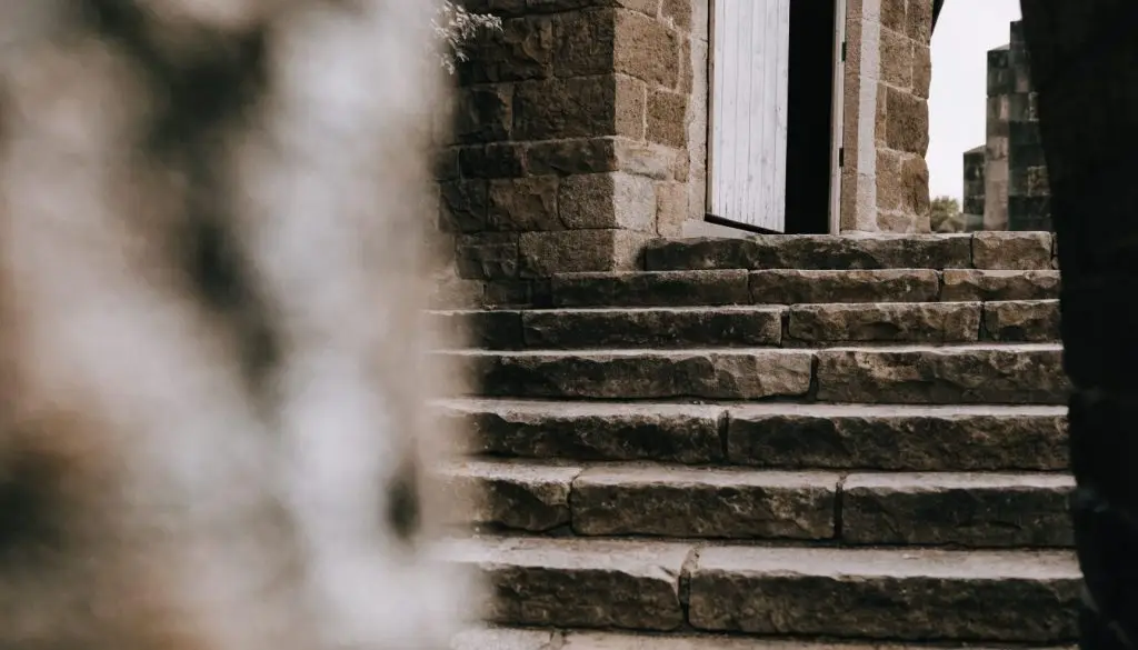 A plain wooden church door standing open on worn stone steps