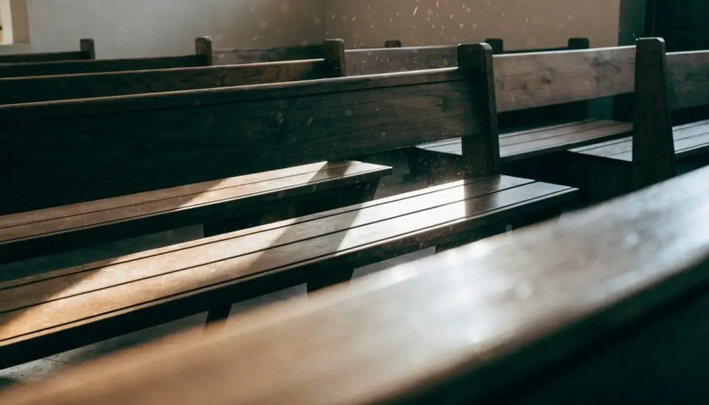 Empty wooden pews lit by morning sunlight in a small church sanctuary.
