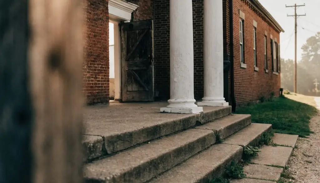 A wooden church door standing open to soft morning light