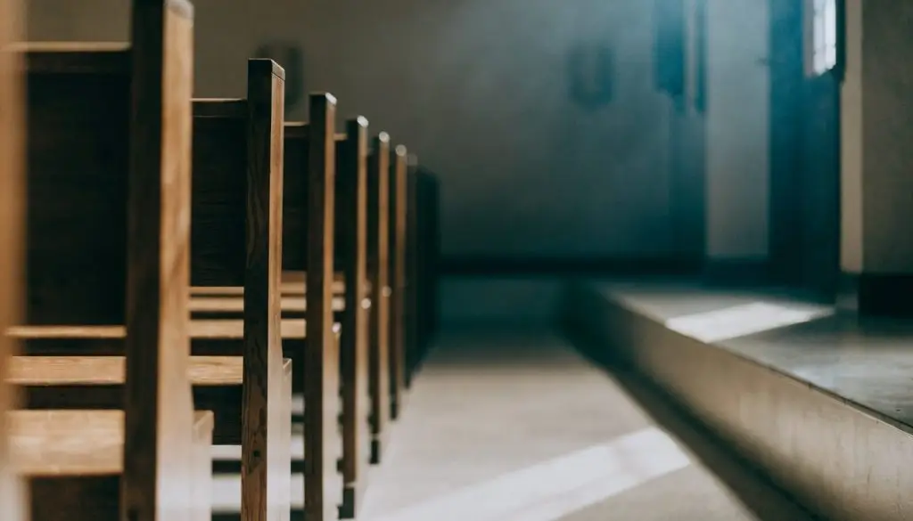 Empty wooden pews in a quiet small-town church sanctuary lit by morning light