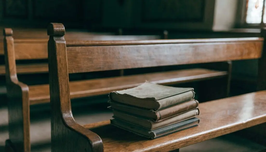 Old hymnals and a worn Bible resting on a wooden pew
